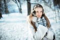 Beautiful woman walking in earmuff, knitted mittens and fur coat have fun in winter forest Royalty Free Stock Photo