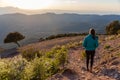 Beautiful woman walking on a path during sunset with mountains on the background Royalty Free Stock Photo