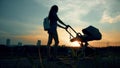 Beautiful woman walking with a stroller in city park at sunset Royalty Free Stock Photo
