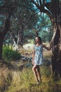 Beautiful woman walking in summer park with olive trees on sunset. Tanned brunette female long hair in white dress Royalty Free Stock Photo