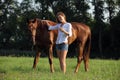 Beautiful woman walks with horse in woods glade at sunset