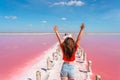 A beautiful woman walks on a salty beach between wooden sticks on a salty pink lake with a blue sky. A peaceful landscape and rela Royalty Free Stock Photo