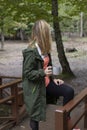 Beautiful woman wanders in the autumn forest and drinks coffee