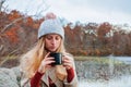 Beautiful woman in warm clothes and knitted hat drinking coffee in autumn park. Woman holding mug of coffee in the hands outdoor Royalty Free Stock Photo