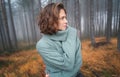 Beautiful woman in warm cozy green sweater in beautiful foggy pine forest Royalty Free Stock Photo