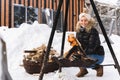 Beautiful woman warming up by the fire pit during cold winter day Royalty Free Stock Photo