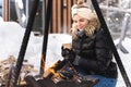 Beautiful woman warming up by the fire pit during cold winter day Royalty Free Stock Photo