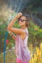 Beautiful woman watering roses with a garden hose Royalty Free Stock Photo