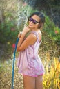 Beautiful woman watering roses with a garden hose