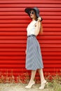 Beautiful woman wearing a black straw hat, sunglasses and striped skirt over red Royalty Free Stock Photo