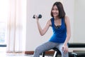 Woman wearing blue and gray sportswear while holding dumbbells looking at camera. fitness slim young woman lifting