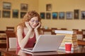 Beautiful woman wearing burgundy casual t shirt and glasses reading text via laptop or searching necessary information, using