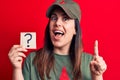 Beautiful woman wearing cap with red star communist symbol holding question mark reminder smiling with an idea or question
