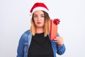 Beautiful woman wearing Christmas Santa hat holding gift over isolated white background with a confident expression on smart face Royalty Free Stock Photo