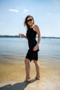 Beautiful woman wearing coctail black dress standing on water lake Royalty Free Stock Photo