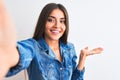 Beautiful woman wearing denim shirt make selfie by camera over isolated white background smiling cheerful presenting and pointing Royalty Free Stock Photo