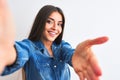 Beautiful woman wearing denim shirt make selfie by camera over isolated white background smiling friendly offering handshake as Royalty Free Stock Photo