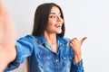 Beautiful woman wearing denim shirt make selfie by camera over isolated white background smiling with happy face looking and Royalty Free Stock Photo