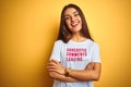 Beautiful woman wearing fanny t-shirt with irony comments over isolated yellow background happy face smiling with crossed arms