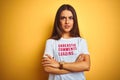 Beautiful woman wearing fanny t-shirt with irony comments over isolated yellow background skeptic and nervous, disapproving