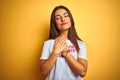 Beautiful woman wearing fanny t-shirt with irony comments over isolated yellow background smiling with hands on chest with closed