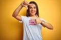 Beautiful woman wearing fanny t-shirt with irony comments over isolated yellow background smiling making frame with hands and