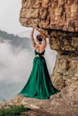 Beautiful woman wearing long green dress standing on the edge of a cliff. Mezmay. Russian mountains. Royalty Free Stock Photo