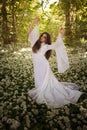 Beautiful woman wearing a long white dress dancing in a forest Royalty Free Stock Photo