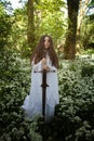 Beautiful woman wearing a long white dress holding a sword Royalty Free Stock Photo