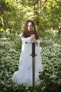 Beautiful woman wearing a long white dress holding a sword Royalty Free Stock Photo