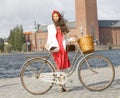 Beautiful woman wearing red dress dress holding a vintage bicycle in front of Stockholm City Hall Royalty Free Stock Photo