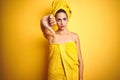 Beautiful woman wearing shower towel on body and head over yellow isolated background looking unhappy and angry showing rejection