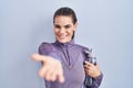 Beautiful woman wearing sportswear holding water bottle smiling cheerful offering palm hand giving assistance and acceptance Royalty Free Stock Photo