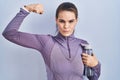 Beautiful woman wearing sportswear holding water bottle strong person showing arm muscle, confident and proud of power