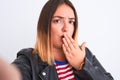 Beautiful woman wearing striped shirt and jacket make selfie over isolated white background cover mouth with hand shocked with Royalty Free Stock Photo