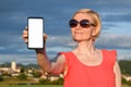 Beautiful woman wearing sun glasses while holding in hand a smartphone