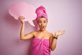 Beautiful woman wearing towel holding cloud speech bubble over isolated pink background very happy and excited, winner expression Royalty Free Stock Photo