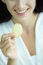 A beautiful woman wearing a towel and a white bathrobe has to eat a snack potato with happy and relaxing on the bed at a