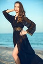 Beautiful woman wearing trendy chiffon oriental black chiffon beach cover up standing on the beach