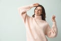 Beautiful woman wearing warm pink sweater on light background. Space for text