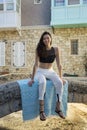 Beautiful woman wearing white loose pants, black crop top and sandals, smiling.