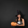 Beautiful woman wearing witch costume with pumpkin for Halloween party on background, space for text Royalty Free Stock Photo