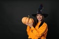 Beautiful woman wearing witch costume with pumpkin for Halloween party on background, space for text Royalty Free Stock Photo