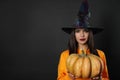 Beautiful woman wearing witch costume with pumpkin for Halloween party on black background Royalty Free Stock Photo