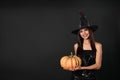 Beautiful woman wearing witch costume with pumpkin for Halloween party on black background Royalty Free Stock Photo