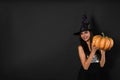 Beautiful woman wearing witch costume with pumpkin for Halloween party on black background Royalty Free Stock Photo