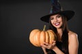 Beautiful woman wearing witch costume with pumpkin for Halloween party on black background Royalty Free Stock Photo