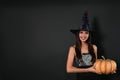 Beautiful woman wearing witch costume with pumpkin for Halloween party on black background Royalty Free Stock Photo