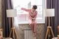 Beautiful woman wears pajamas with a glass of red wine sits on the windowsill near the beautiful window at home. Stay Royalty Free Stock Photo