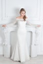 Beautiful woman in wedding dress standing near decorative fireplace Royalty Free Stock Photo